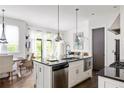 Modern kitchen features stainless steel appliances, white cabinets and black countertops and overlooks the dining area at 9121 Selborne Ln, Chattahoochee Hills, GA 30268