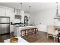 Open kitchen features stainless steel appliances, center island with dark countertops and bar stool seating at 9121 Selborne Ln, Chattahoochee Hills, GA 30268