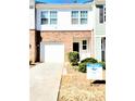 Two-story townhouse featuring a brick facade, attached garage, and neatly landscaped front yard with a for-sale sign at 6408 Kennonbriar Ct, Lithonia, GA 30058