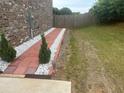 Property features manicured side yard with landscape rocks and an attractive brick walkway at 3419 In Bloom Way, Auburn, GA 30011