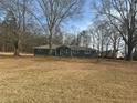 Landscaped front yard of a cozy single-story home, surrounded by mature trees and a grassy lawn at 9588 Poston Rd, Jonesboro, GA 30238