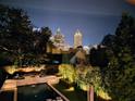 This backyard features a pool, landscaping, and nighttime city views at 115 17Th Ne St, Atlanta, GA 30309