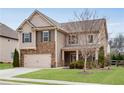 Traditional home featuring a stone facade, a two-car garage, and a neatly kept lawn at 4080 Huron Dr, Cumming, GA 30028