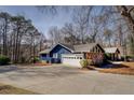 Blue home with garage door, stone details, mature trees, and a well-maintained driveway at 825 Sugar Creek Se Way, Conyers, GA 30094