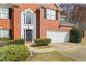 Close up of the front of a brick home with a black door and a two-car garage at 1390 Bridle Path Dr, Lawrenceville, GA 30045