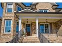 Inviting front porch with stone accents, a wooden door, and classic columns offering curb appeal at 2300 Hopehaven Way, Hoschton, GA 30548