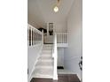 Well-lit staircase with carpeted stairs, a white railing, and an upper and lower landing at 41 Silverthorne Ct, Douglasville, GA 30134