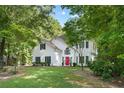 Beautiful home with white siding, a red door, and a sprawling green lawn surrounded by mature trees at 76 Barrington Farms Pkwy, Sharpsburg, GA 30277