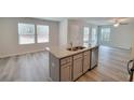 Open concept kitchen with island, granite counters, stainless appliances, and wood-look floors at 425 Camella Cir, Mcdonough, GA 30252