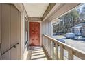 View of a covered porch area with a red door and view of the parking area and surrounding buildings at 3852 Woodridge Way, Tucker, GA 30084