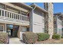 Exterior view showcasing the entrance to a multi-story condo building and landscaped foliage at 3852 Woodridge Way, Tucker, GA 30084