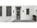 A charming gray front door with transom window and wreath, flanked by two large windows at 11279 Serenbe Ln, Chattahoochee Hills, GA 30268