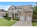 Attractive two-story brick home boasting a lush front lawn, two-car garage, and welcoming entrance at 3286 Sweetleaf Ln, Buford, GA 30519