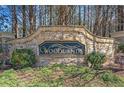Stone sign for the Woodlands community with manicured greenery at 239 Sumac Trl, Woodstock, GA 30188