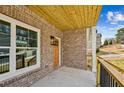 Covered brick front porch with wood ceiling, black railing, and entry door at 3128 Stonegate Sw Dr, Atlanta, GA 30331