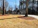 Home on a grassy lot with mature trees and a paved driveway at 494 West Ave, Bowdon, GA 30108