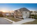 View of the left side of a charming two-story home with stone and shingle exterior and manicured lawn at 4440 Croftshire Pl, Cumming, GA 30040