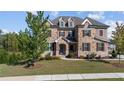 Beautiful two-story home featuring a stone facade, manicured lawn, and charming shuttered windows at 4440 Croftshire Pl, Cumming, GA 30040