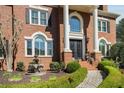 Close-up of a brick home with manicured hedges, decorative fountain, and ornate front door at 5400 Saint Lyonn Pl, Marietta, GA 30068