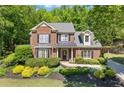 Classic brick home featuring manicured front yard with lush landscaping and charming shutters at 2802 Nettle Ln, Buford, GA 30519
