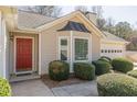 Close up of home's entrance featuring a red door, black awning, and manicured bushes at 7238 Hummingbird Ln, Winston, GA 30187
