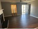A gray-walled living room with wood flooring, a ceiling fan, a fireplace, and a door to the outside at 6682 Biscayne Blvd, Rex, GA 30273