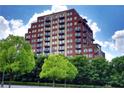 Multi-story brick building with balconies, trees in the foreground, and a partly cloudy sky at 3180 Mathieson Ne Dr # 806, Atlanta, GA 30305