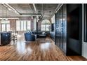 Open-concept living room featuring exposed brick, hardwood floors, and a comfortable couch at 3180 Mathieson Ne Dr # 806, Atlanta, GA 30305