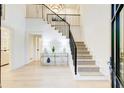 Bright foyer featuring a grand staircase with iron railings, light hardwood floors, and modern chandelier at 6090 River Chase Cir, Atlanta, GA 30328