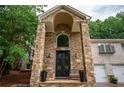Grand stone entrance with arched doorway and double doors, complemented by a lush green lawn at 3290 Coachmans Ne Way, Roswell, GA 30075