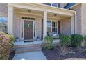 Inviting covered front porch with brick accents and a charming seating area at 194 Lakestone Parkway, Woodstock, GA 30188