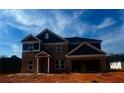 Two-story brick home featuring a two-car garage and covered front porch under a clear sky at 3191 Morris Hills Dr, Dacula, GA 30019