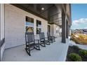 Charming covered front porch with classic rocking chairs at 7560 Wild Violet Dr, Cumming, GA 30040
