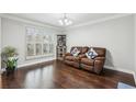 Comfortable living room featuring hardwood floors, a leather sofa, and natural light from the beautiful window at 960 Sugar Meadow Dr, Sugar Hill, GA 30518