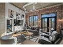 Living room features exposed brick, hardwood floors, a comfortable sofa, and bright windows with a neighborhood view at 3235 Roswell Ne Rd # 710, Atlanta, GA 30305