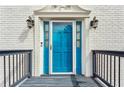 Close-up of a stylish blue front door with decorative accents, a modern door bell, and classic sconces at 4646 Breakwater Trl, Marietta, GA 30066