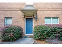 Inviting townhouse entrance with blue door, decorative bushes, and brick facade at 805 Pleasant Hill Rd # 222, Lilburn, GA 30047
