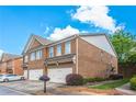 Brick townhouse showcasing a well-manicured lawn and attached garages on a sunny day at 805 Pleasant Hill Rd # 222, Lilburn, GA 30047