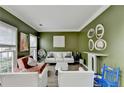 A living room with a large olive green accent wall, crown moulding, and many seating options at 901 Blue Sky Rdg, Snellville, GA 30078