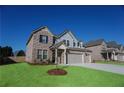 Two-story brick home with a three-car garage and a freshly planted tree in the front yard at 2256 Cadenza Cir, Dacula, GA 30019