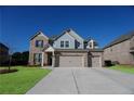 Inviting two-story brick home featuring a three-car garage and a well-manicured lawn at 2256 Cadenza Cir, Dacula, GA 30019
