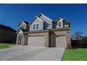 Two-story brick home showcasing a spacious three-car garage and manicured landscaping at 2256 Cadenza Cir, Dacula, GA 30019
