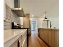 Modern kitchen featuring sleek appliances, wood-grain cabinets, a tile backsplash, hardwood floors, and an island with a sink at 3629 Stewart Rd, Atlanta, GA 30340