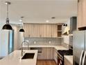 A modern kitchen featuring wood-grain cabinets, quartz countertops, stainless steel appliances, an island, and stylish pendant lighting at 3629 Stewart Rd, Atlanta, GA 30340