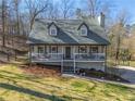 Charming home featuring a cozy front porch, grey siding, dormer windows and a well-manicured lawn surrounded by mature trees at 504 Hanover Ct, Woodstock, GA 30188