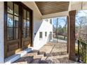 Brick steps lead to a covered porch featuring a dark wood door, columns, and a stylish brick floor at 1200 Primrose Park Rd, Sugar Hill, GA 30518