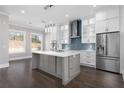 A modern white kitchen with stainless steel appliances, a center island, and a blue backsplash at 1200 Primrose Park Rd, Sugar Hill, GA 30518