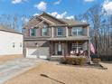 Two-story brick home featuring an attached two-car garage and cozy covered front porch at 5160 Bucknell Trce, Cumming, GA 30028