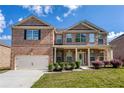 Attractive brick two-story home with a covered porch, well-kept lawn and landscaping, and an attached garage at 3772 Sunbridge Dr, Snellville, GA 30039