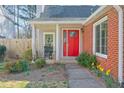 Inviting front porch with a red door, brick facade, and blossoming spring flowers at 245 Dennis Dr, Alpharetta, GA 30009